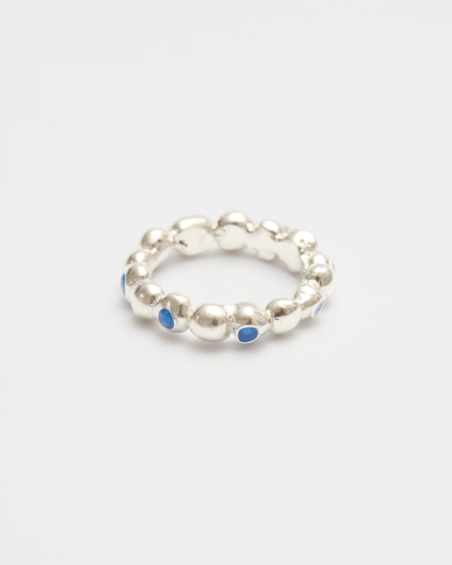 A silver beaded ring with small blue inlay details, photographed on a clean white background.