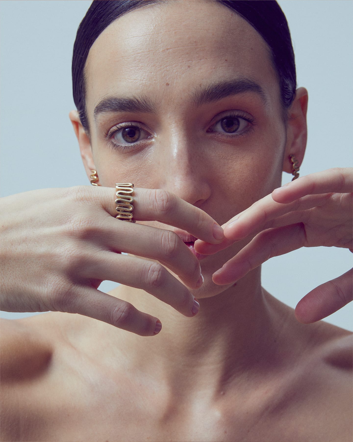 Model wearing gold Arpa ring and matching earrings