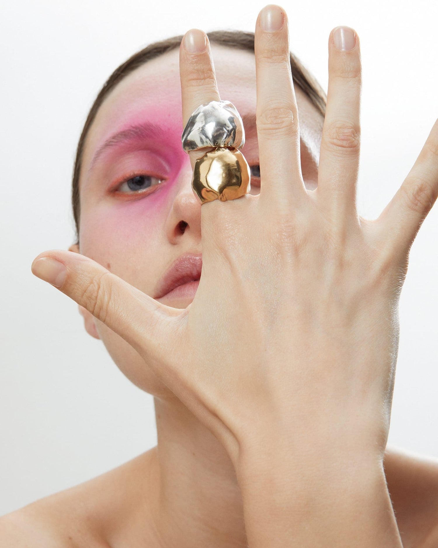 Model wearing LMJ Baloon Rings in silver and gold, stacked across two fingers