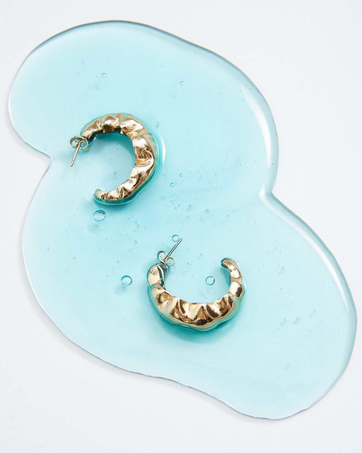 LMJ Bubble Maxi silver earrings styled on blue material, echoing the collection's fluidity.