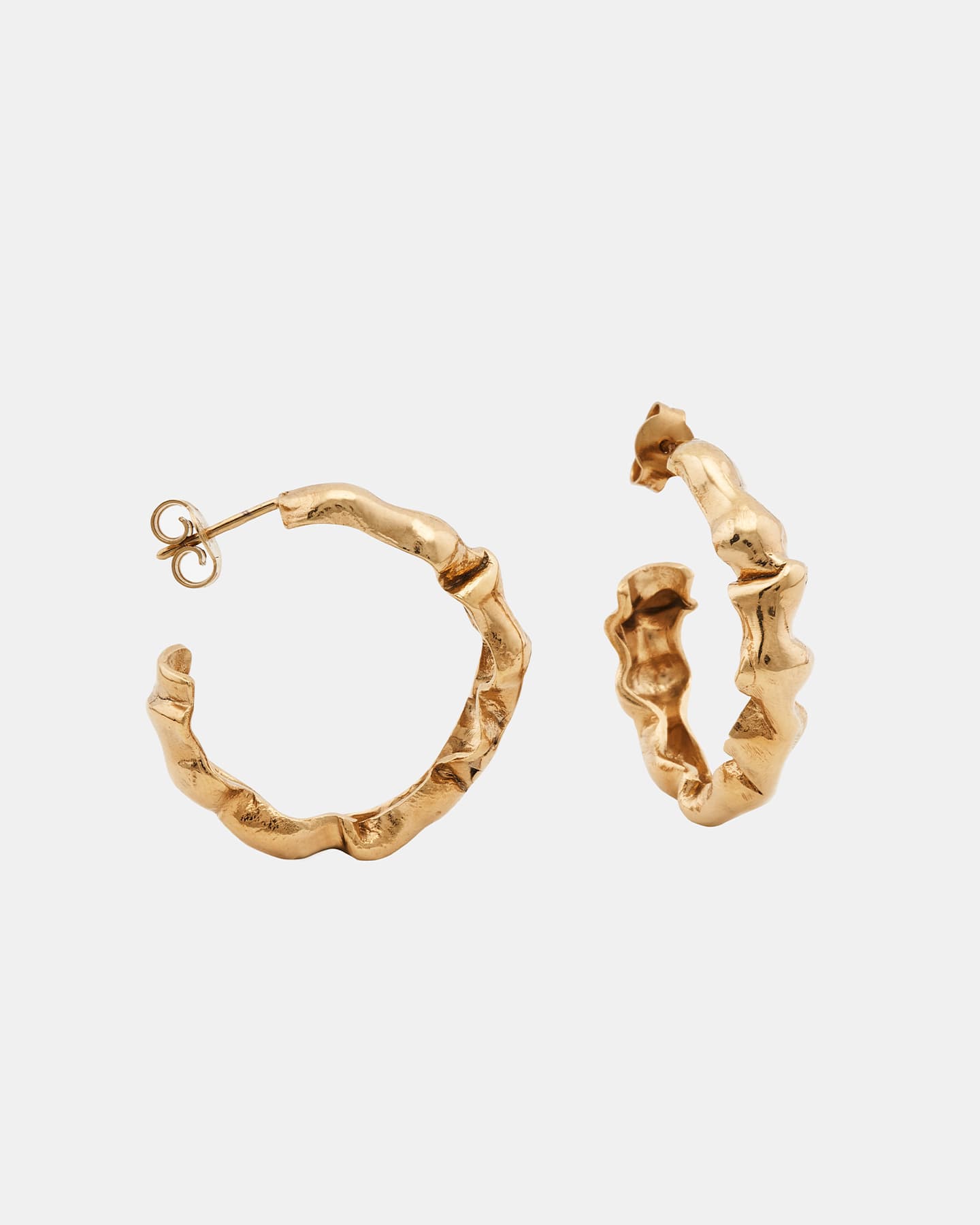 Alternate angle of LMJ Bubble Mini earrings in warm gold, floating over glossy blue styling gel.