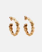 Alternate angle of LMJ Bubble Mini earrings in warm gold, floating over glossy blue styling gel.