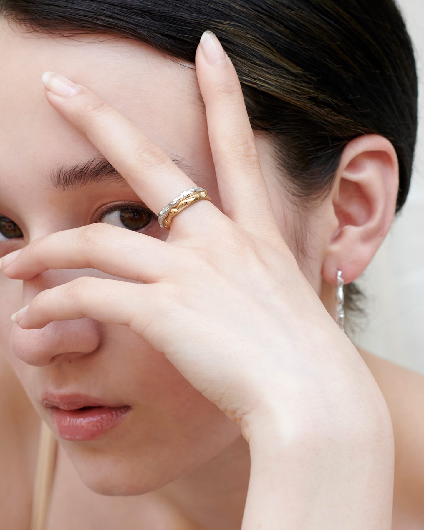 Model wearing a stack of drop rings in silver and gold.