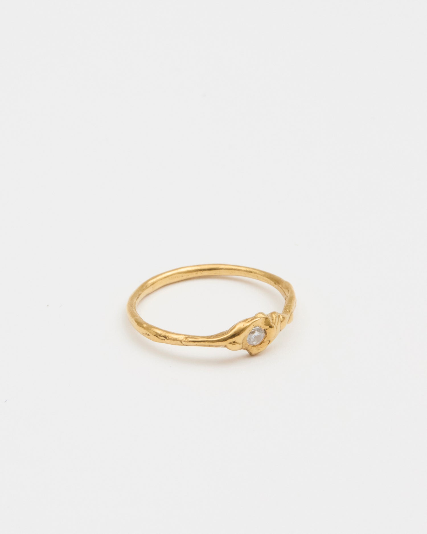 Gold ring with a small gemstone on a light gray background