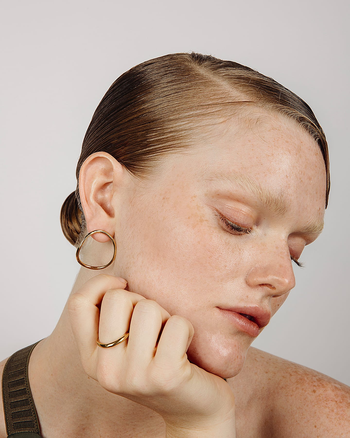 Woman wearing the LMJ Hollow earrings and Hollow Ring in gold, with a neutral background.