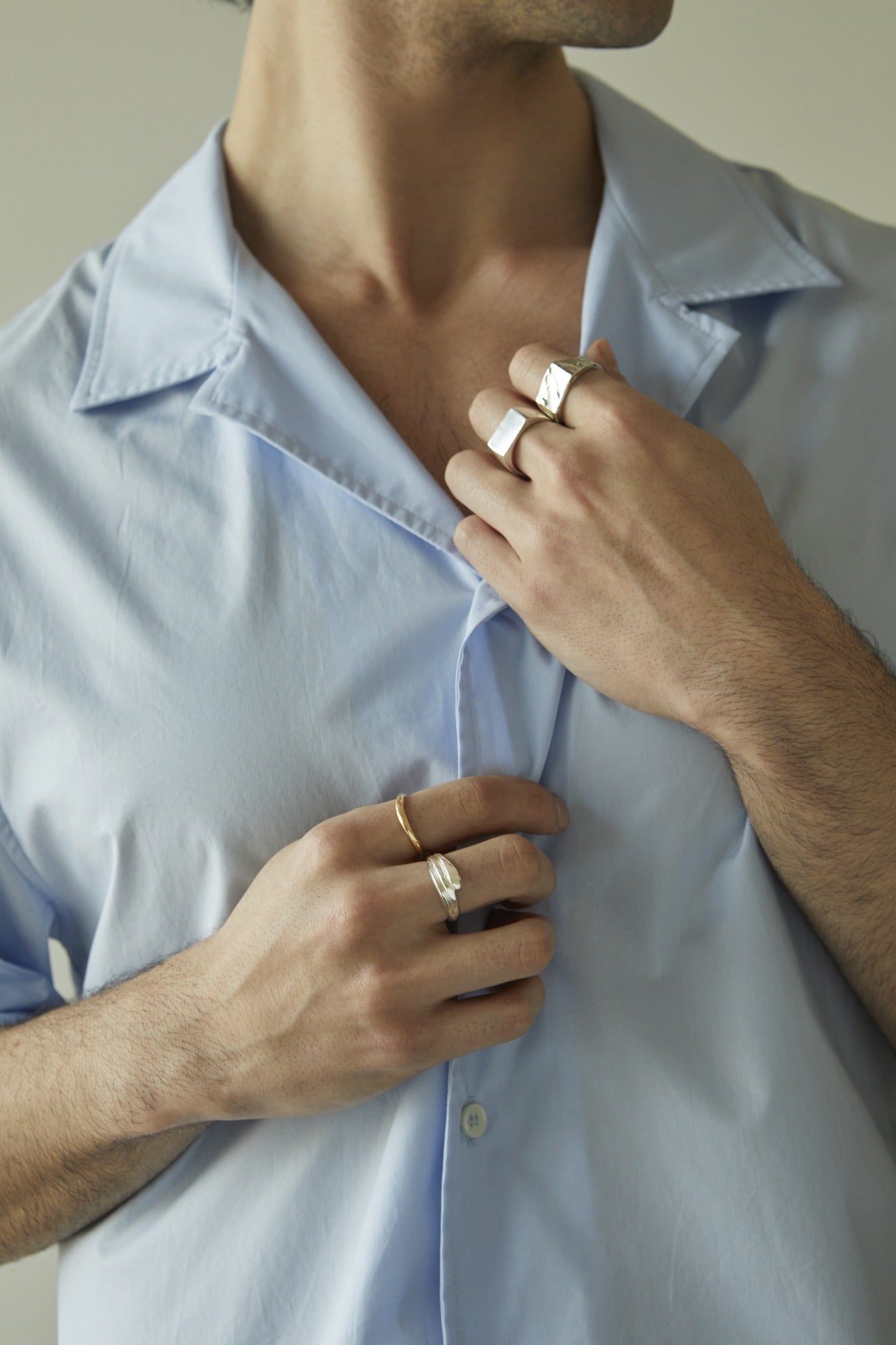 LMJ Person wearing a light blue shirt with a close-up of hands adjusting the collar.