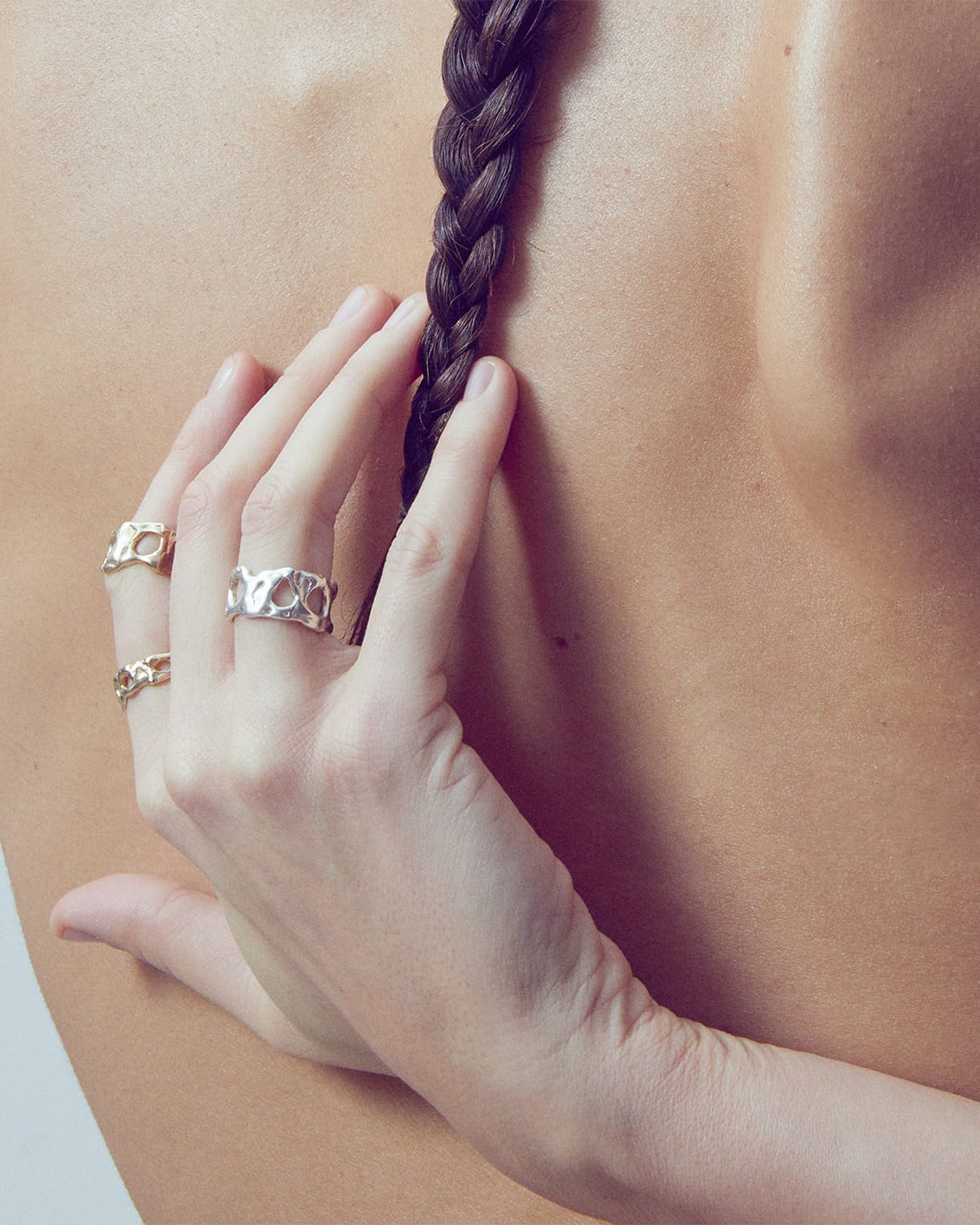 Hand with rings holding a braided hair against a blurred background waring the LMJ Nebula Rings