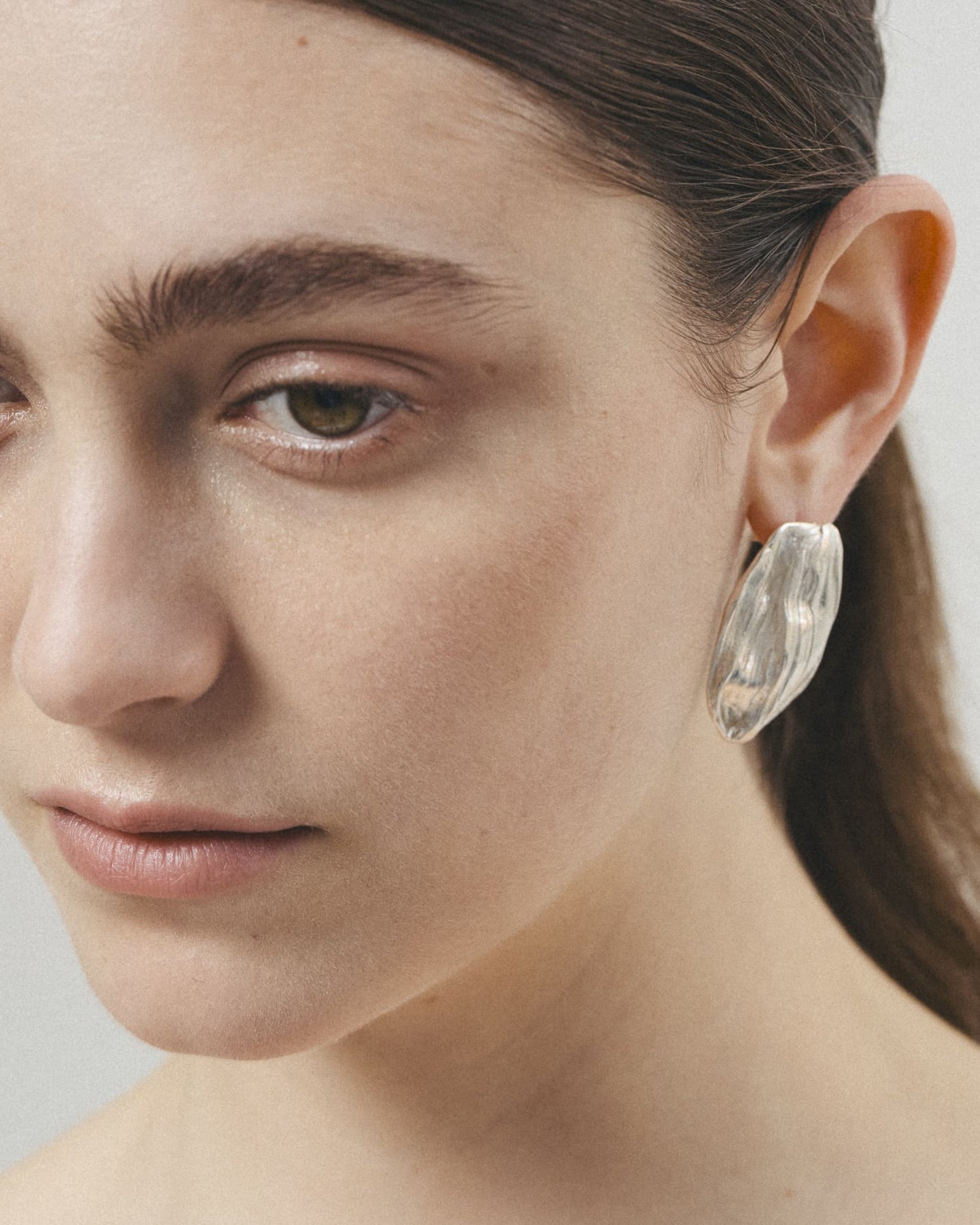 Model wearing LMJ Petalo Maxi Earrings in silver – bold and reflective organic form