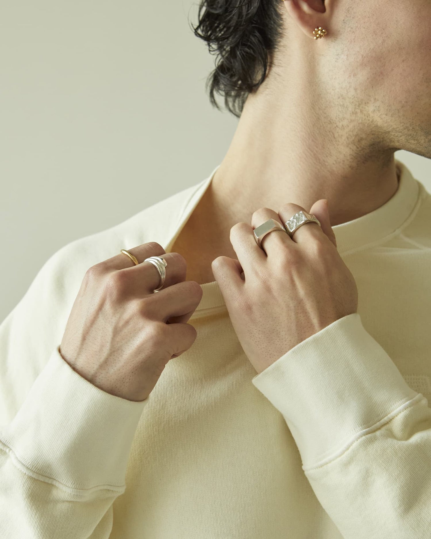 LMJ Close-up of a person wearing multiple rings on a neutral background