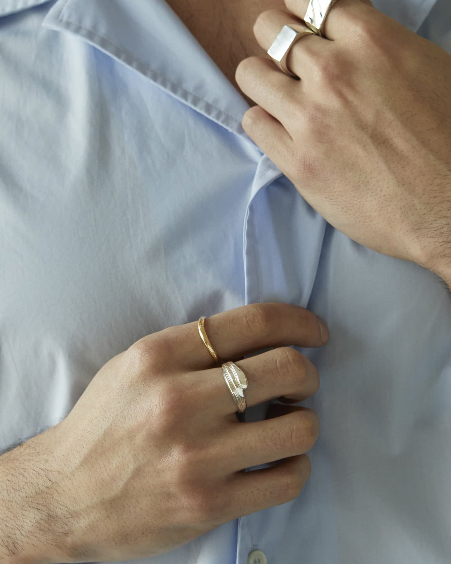 LMJ Close-up of hands with rings on a light blue shirt