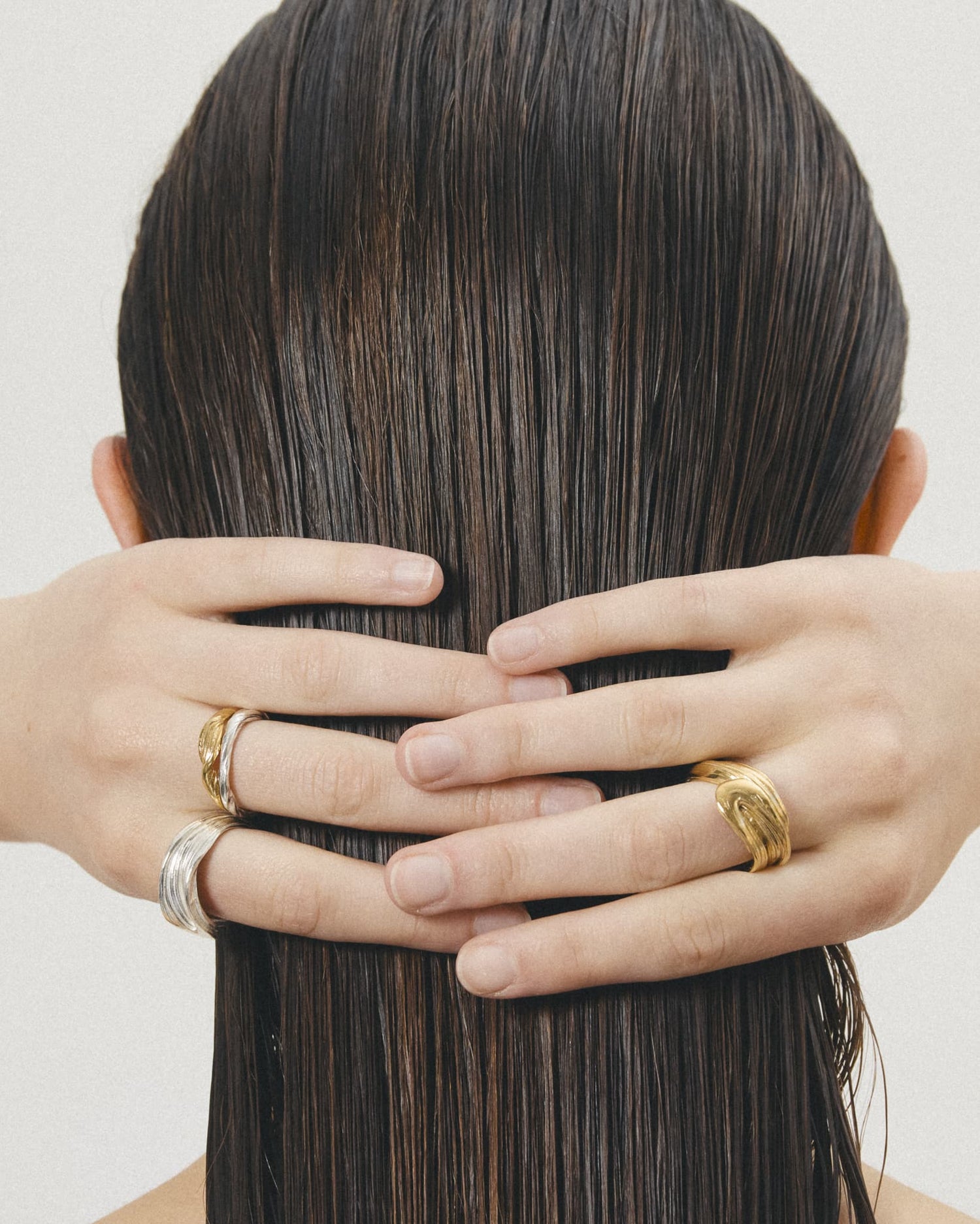Model with wet hair showing LMJ Vortex Rings in gold and silver – bold and sculptural forms