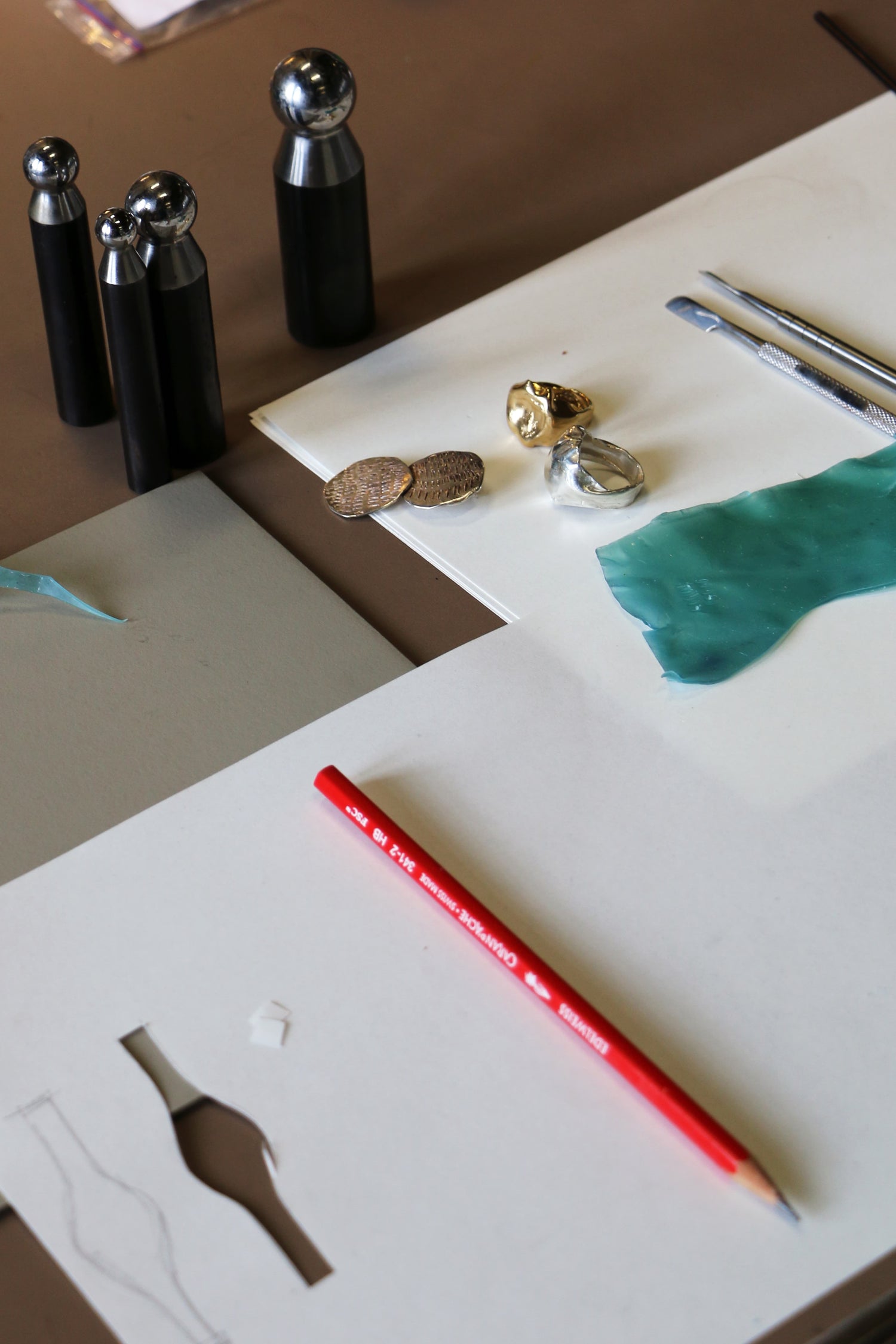 Art supplies including a red pencil, rings and wax pieces during the LMJ wax carving jewelry workshop.