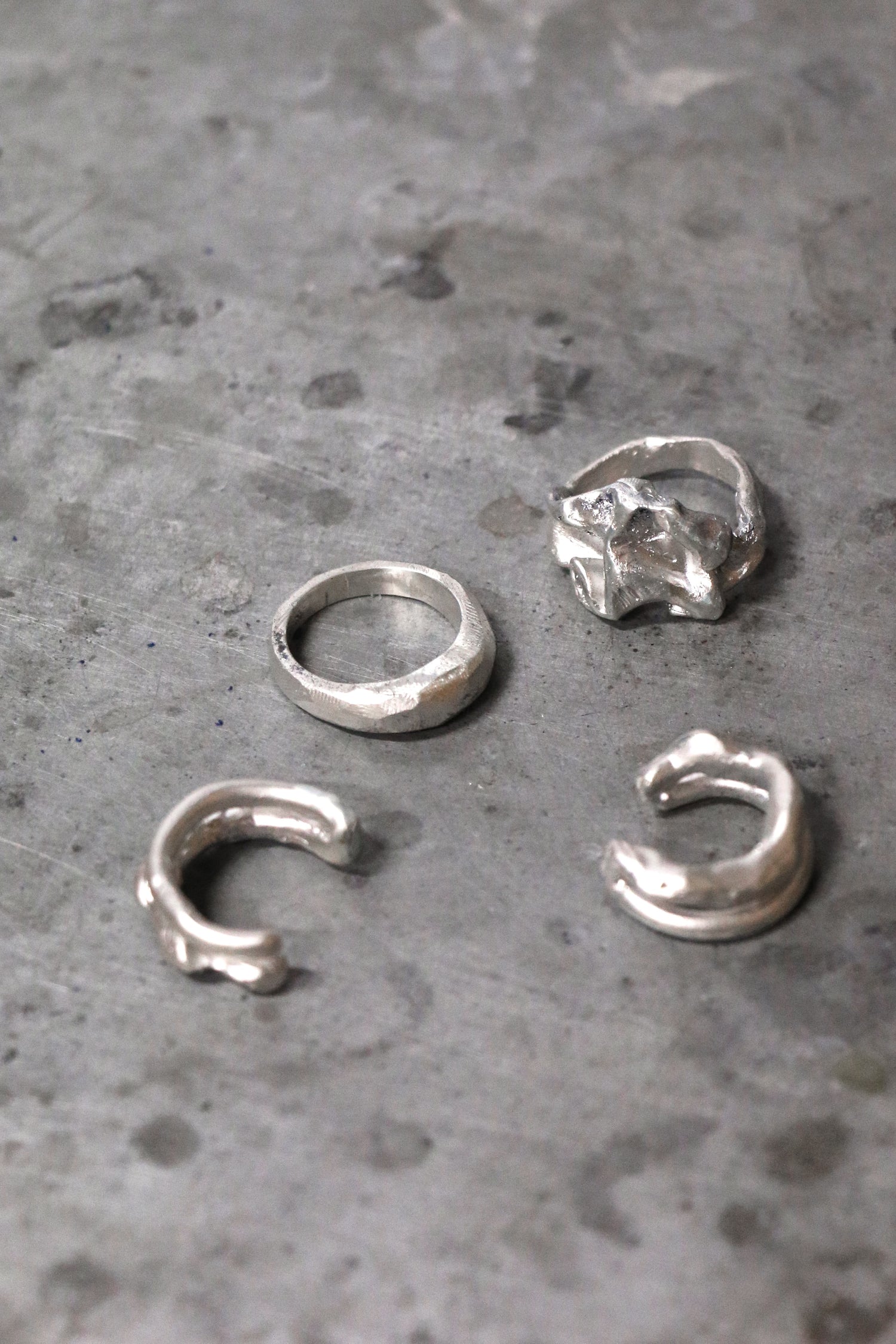 Five silver rings on a textured gray surface